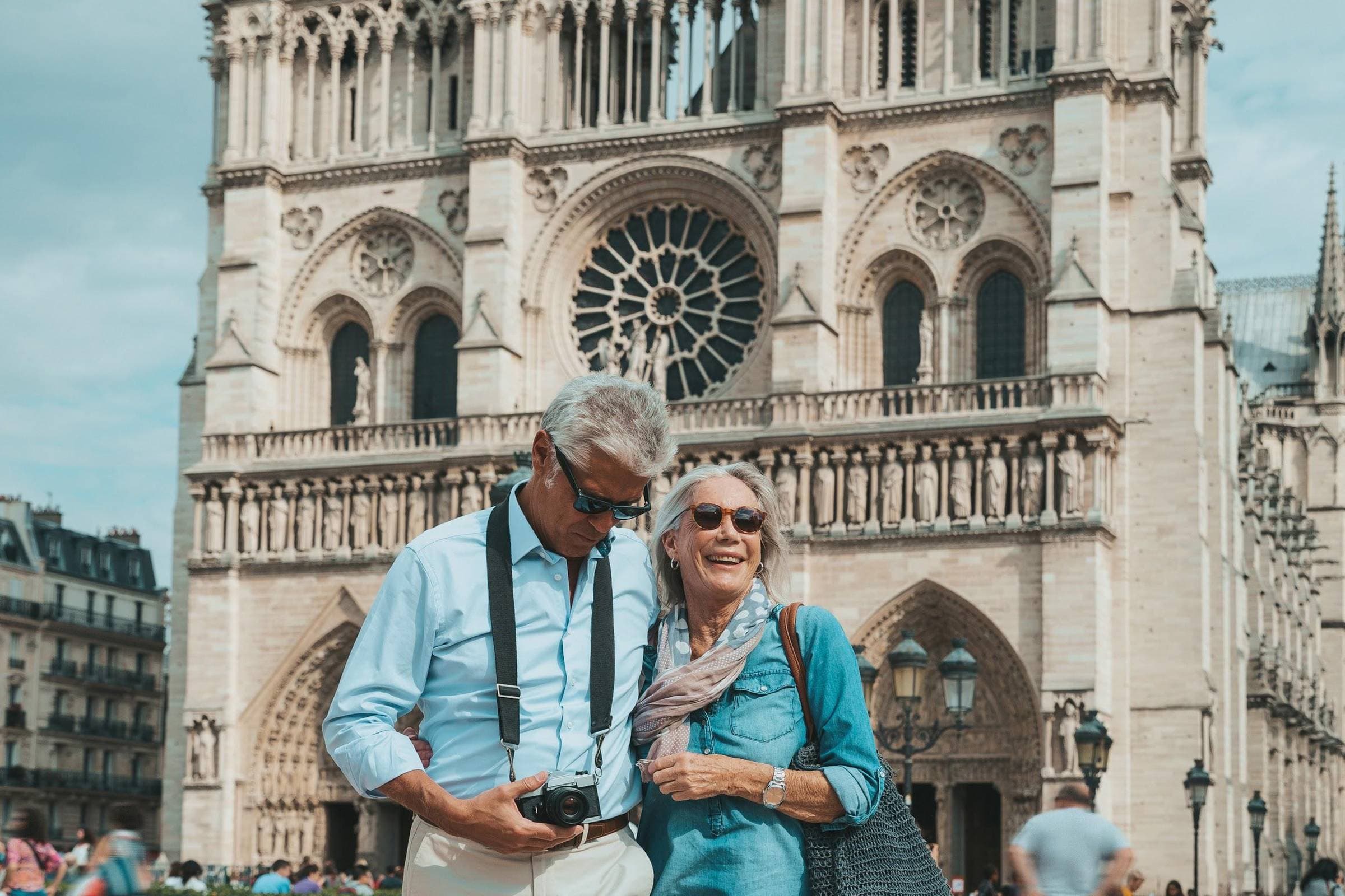 Couple reviewing photos on a camera in front of Notre-Dame Cathedral in Paris.