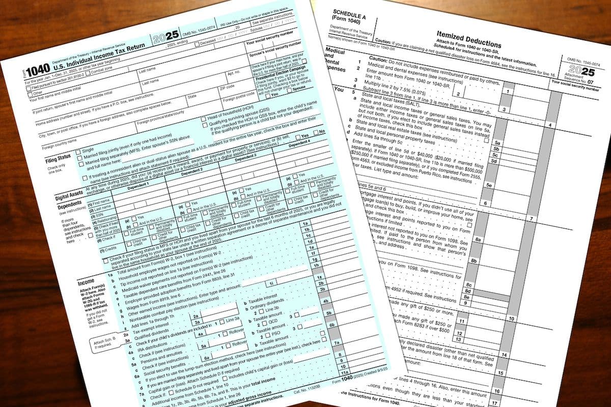 IRS Form 1040 and Schedule A tax documents laid out on a wooden surface