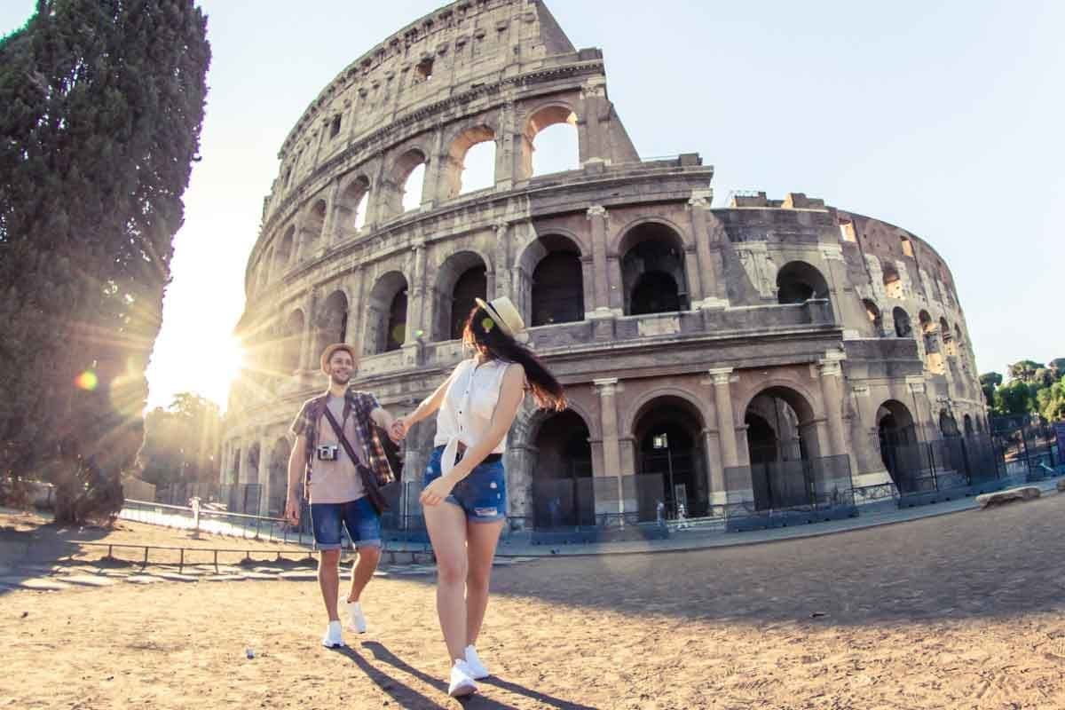 A couple walks in front of the Colosseum in Rome, Italy