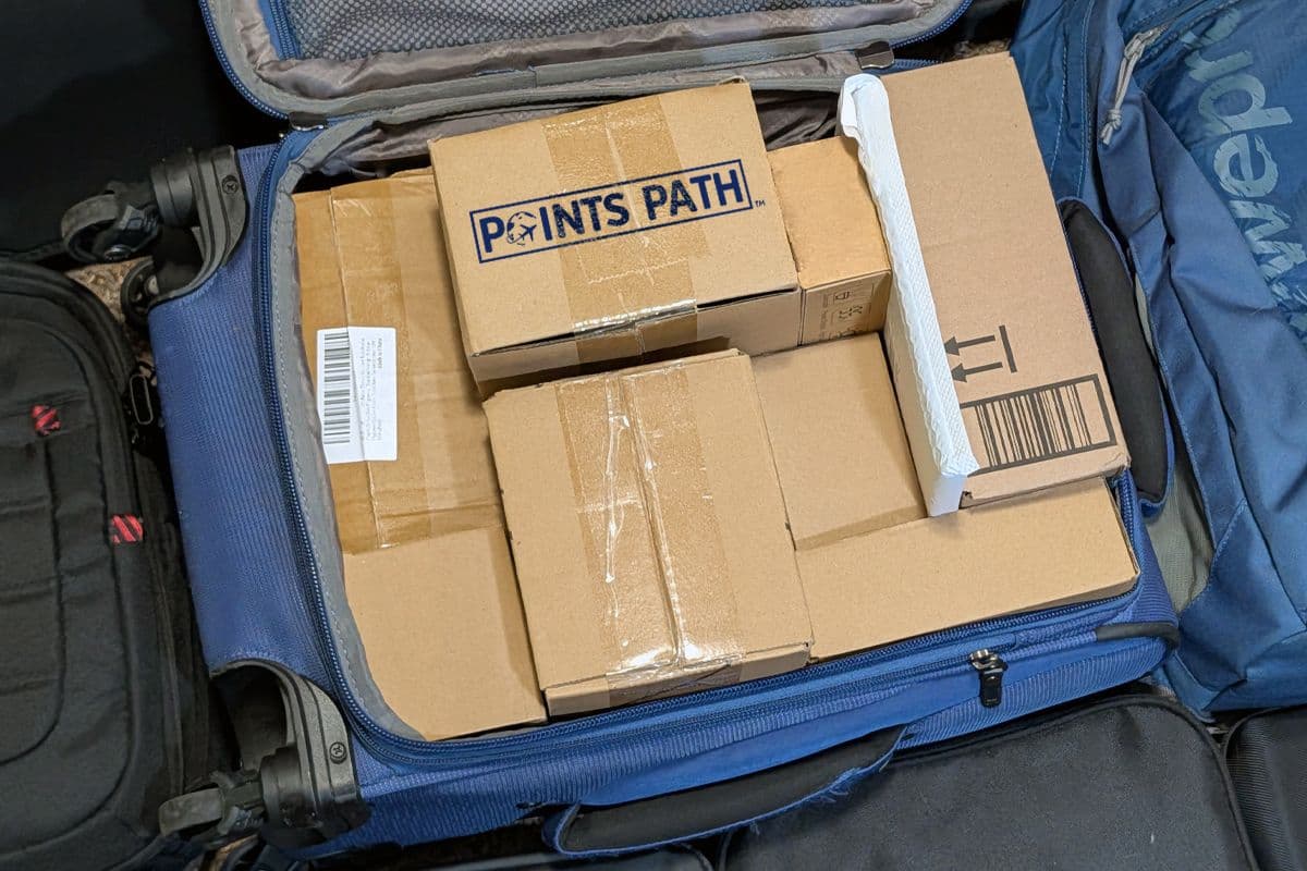 A blue suitcase is full of brown retailer-shipped packages. One has the Points Path logo on it.