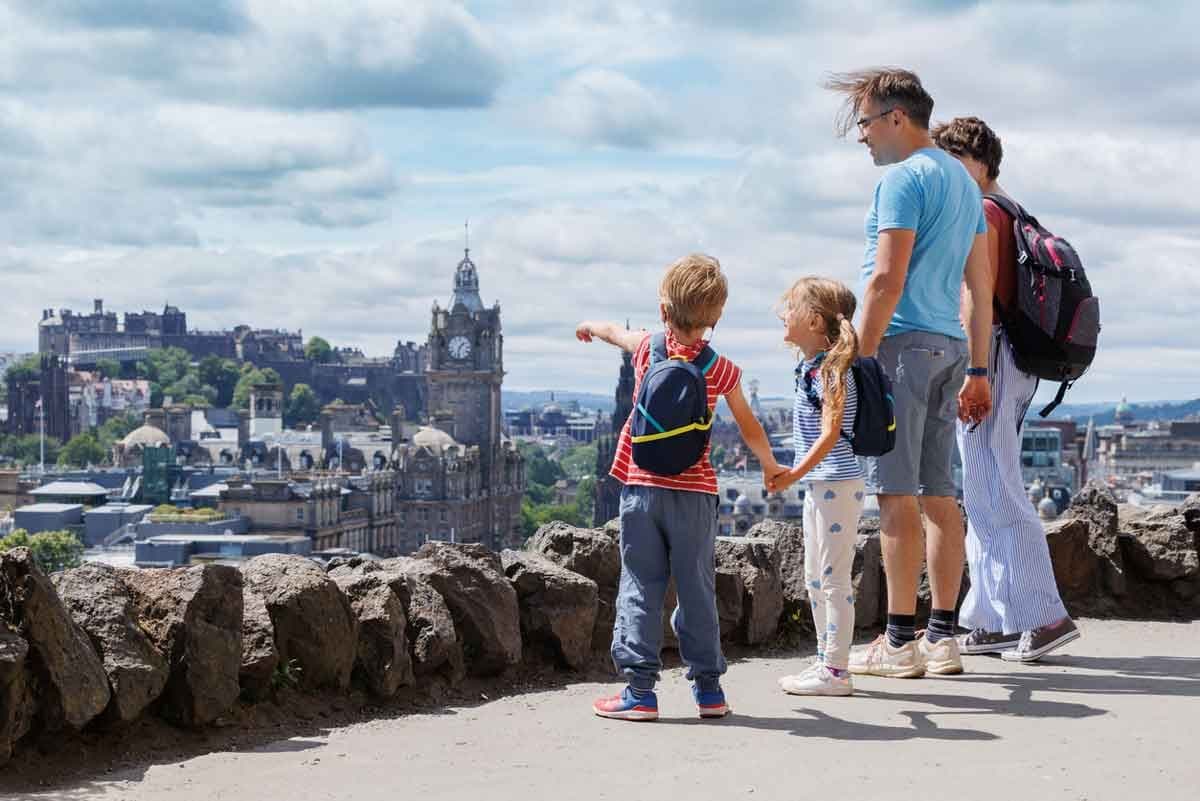 A family of four looks out at the cityscape of Edinburgh, Scotland.