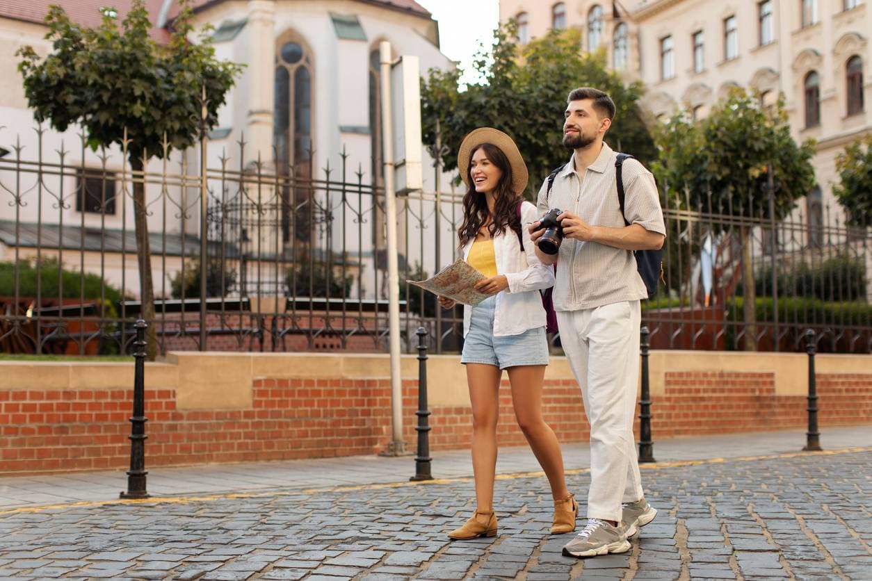 Couple exploring a European city on foot, holding a paper map and camera