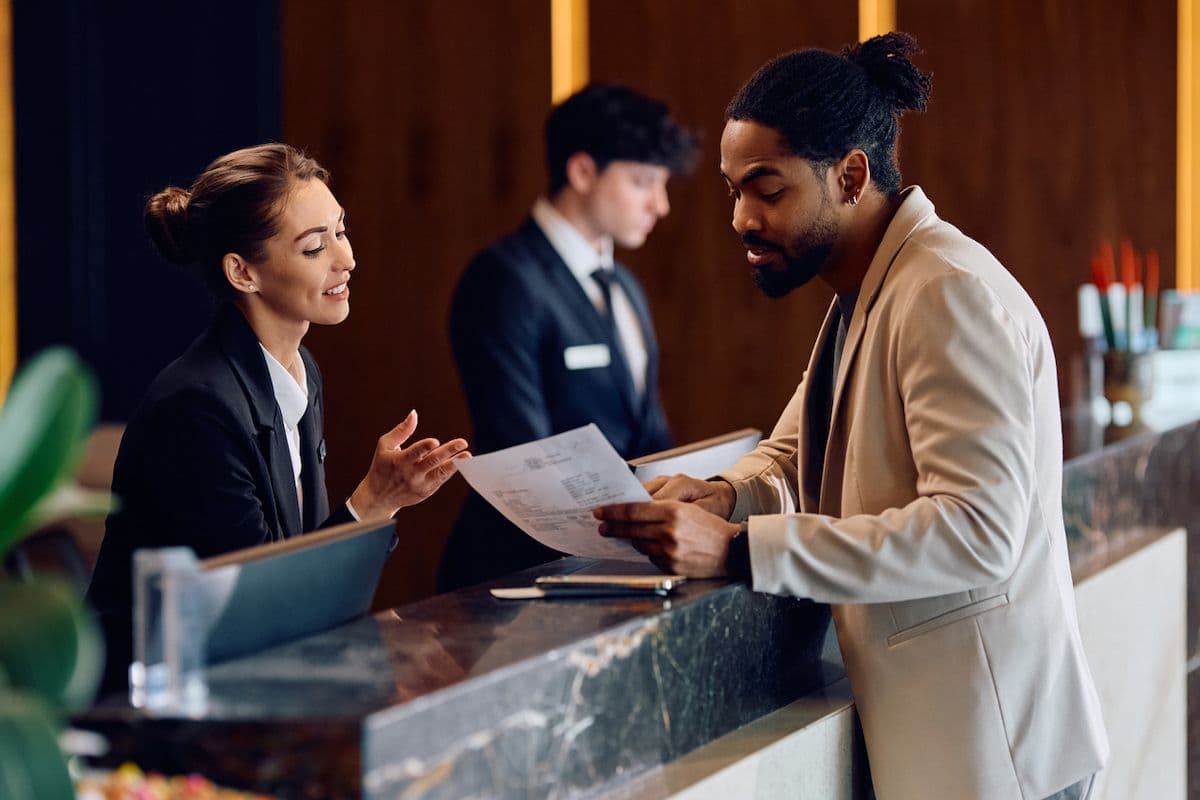A man reviews the bill at a hotel check-in desk.