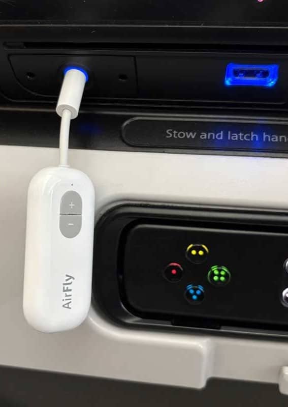 An Airfly Pro headphone adapter plugged into the seatback headphone jack on a plane.