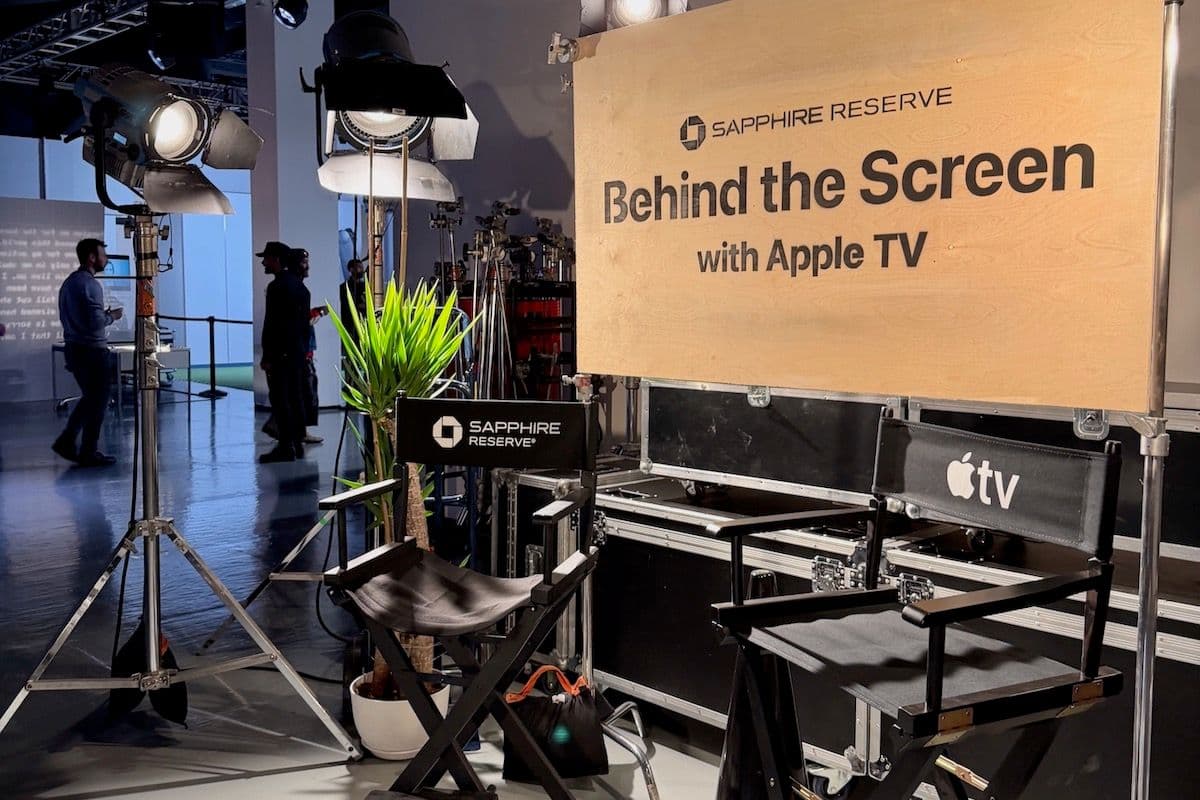 Signage for the Sapphire Reserve “Behind the Screen” event with Apple TV, featuring director’s chairs, studio lighting, and production equipment set up for cardholders.