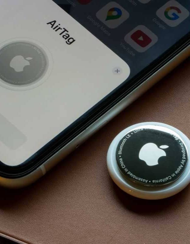 An Apple AirTag next to an iPhone, whose screen is prompting the user to connect the two devices.