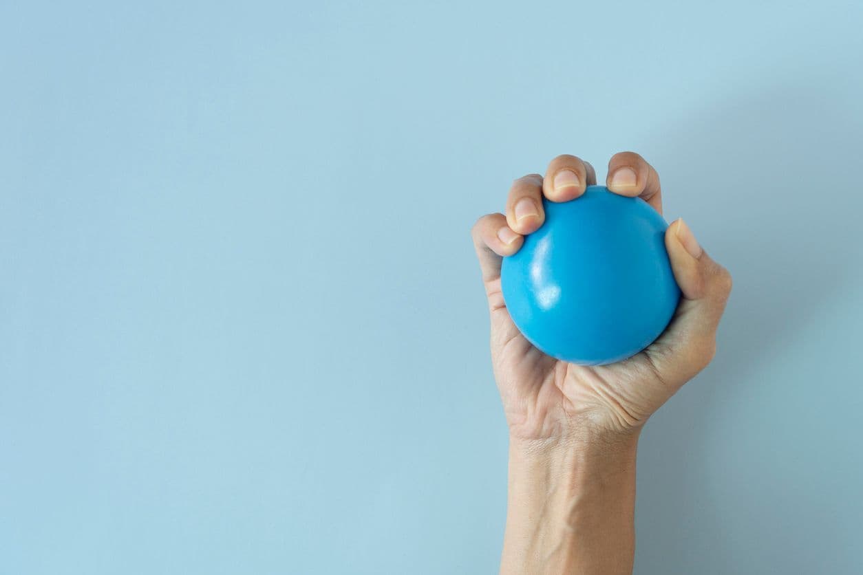 A hand holds a blue stress ball