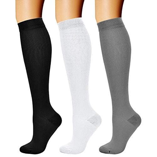 Three knee-high compression socks displayed on legs, one each in black, white, and gray.