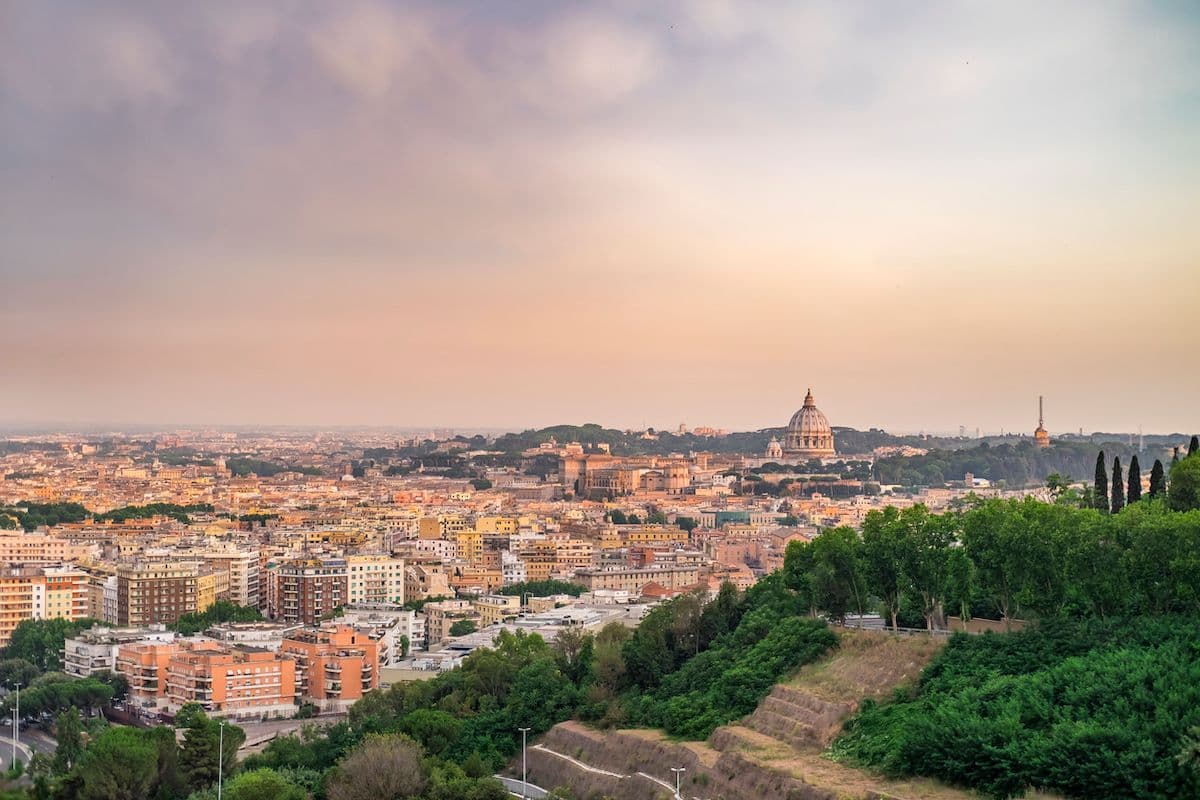 Golden-hour view across Rome rooftops toward St. Peter's dome
