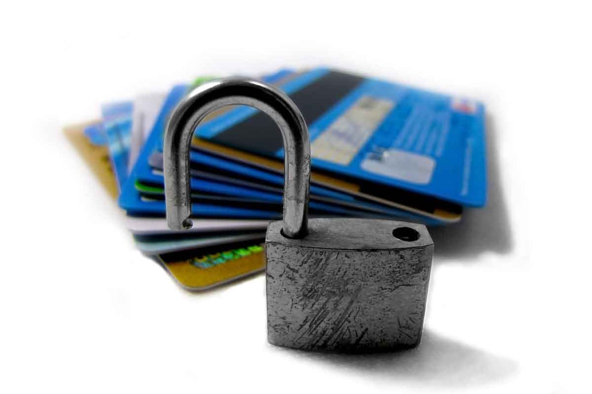An unlocked lock sitting in front of a pile of credit cards