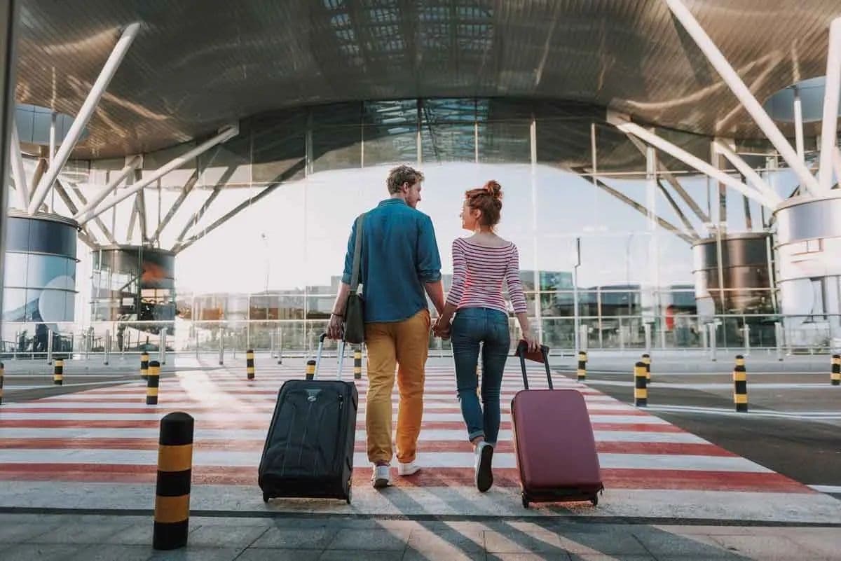 A couple with suitcases walking into an airport together