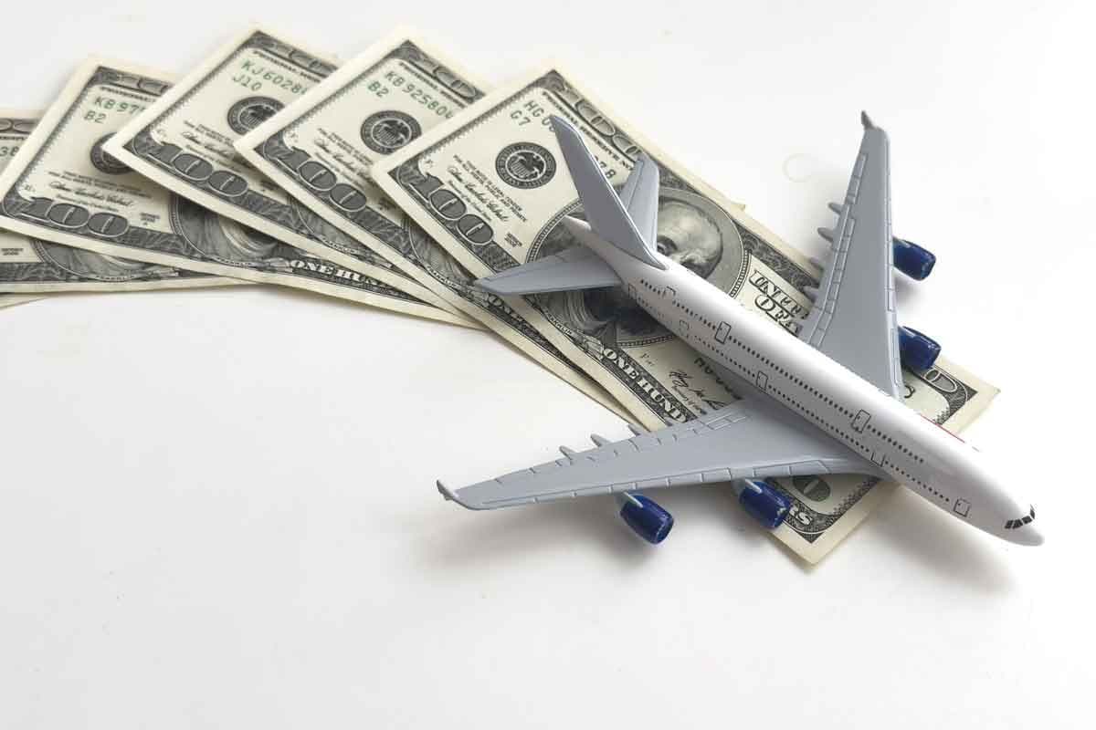 A model airplane sitting on top of several fanned-out hundred dollar bills.