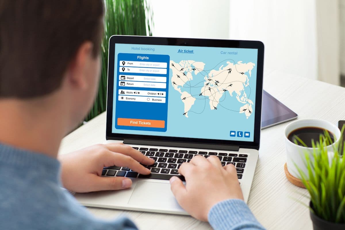 Person booking flights on a laptop, reviewing routes on a world map.